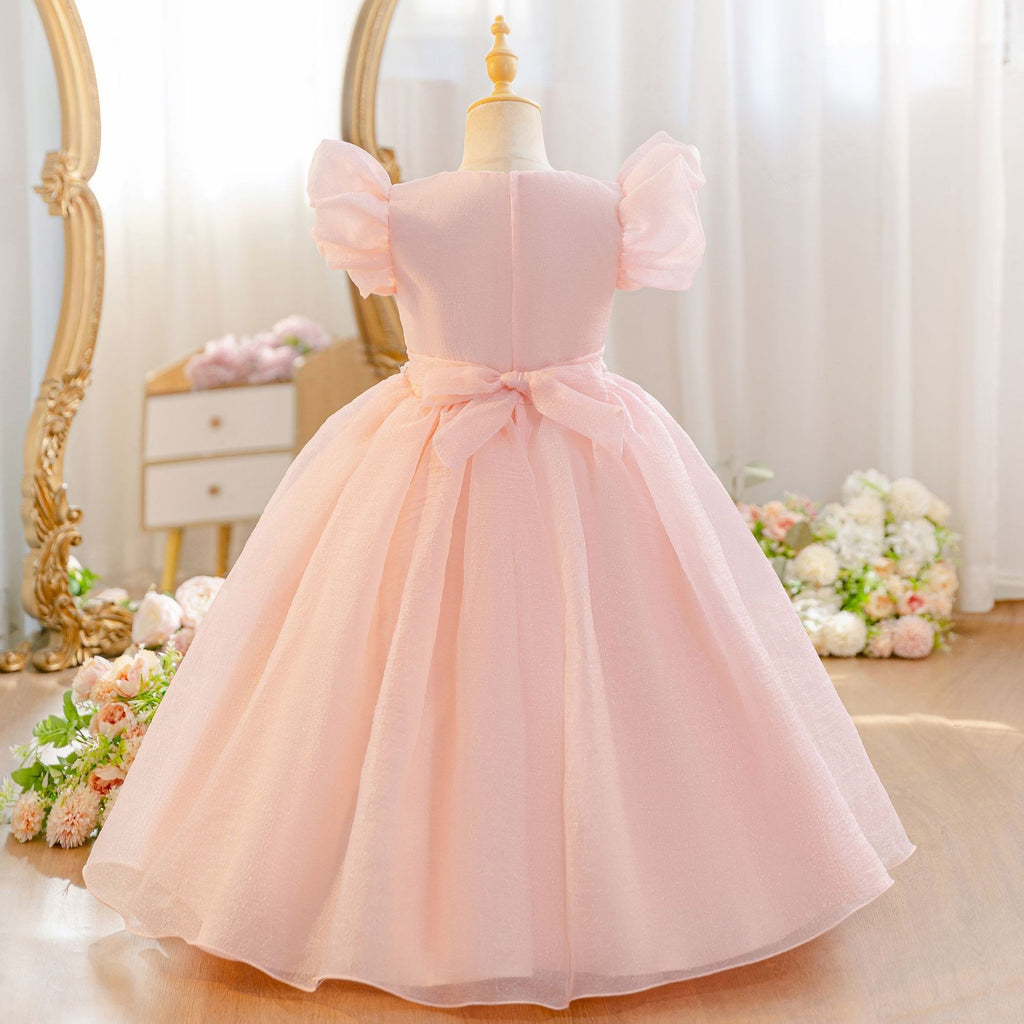 Shrimp pink girls party dress with a rose trimmed neckline, angled side view.