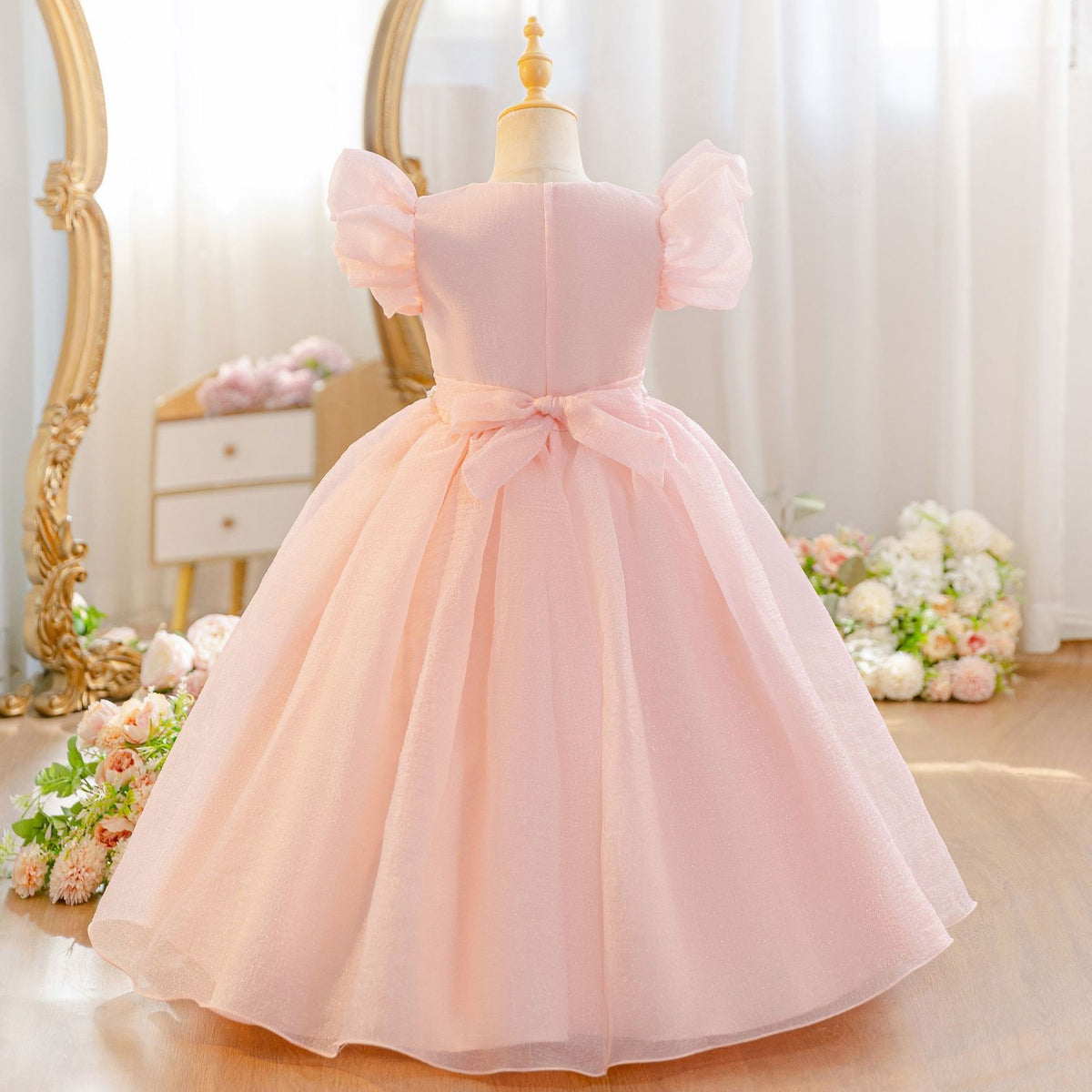 Shrimp pink girls party dress with a rose trimmed neckline, angled side view.