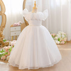 White tulle flower girl dress with 3D roses and a pearl belt, front view, for a ceremony.