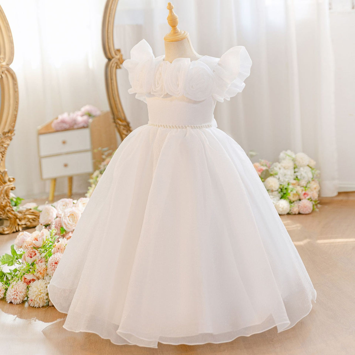 White dress for girls in soft tulle with a pearl waist belt, angled view.
