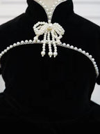 Close-up of the pearl bow collar with pearl tassels on a black velvet girls dress, designed for birthday parties.