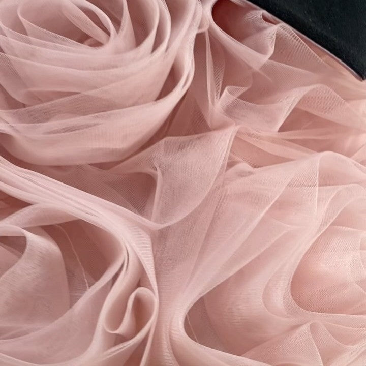 Close-up of the rolled blush pink tulle rosettes on the skirt of this princess dress for girls.