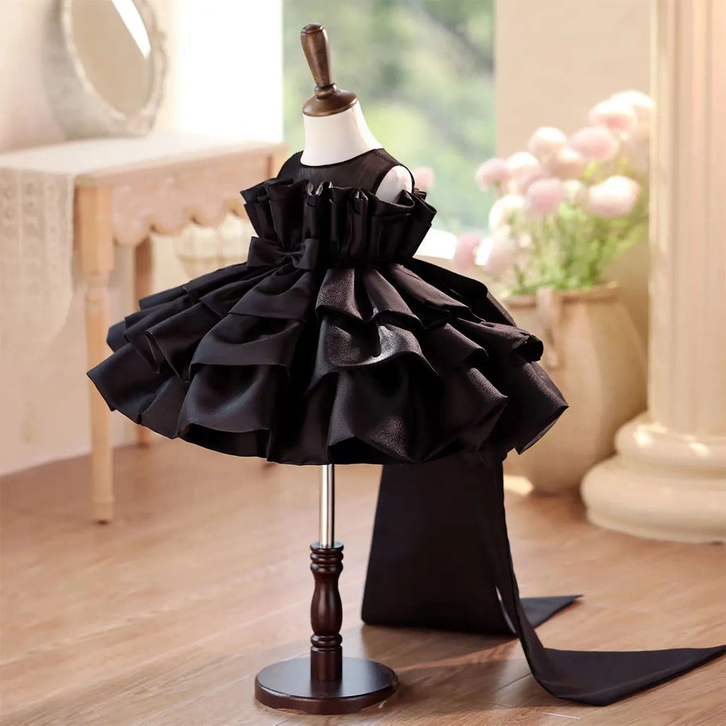 Black tiered satin princess dress for girls with the train trailing behind, side view.