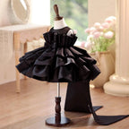 Black tiered satin princess dress for girls with the train trailing behind, side view.