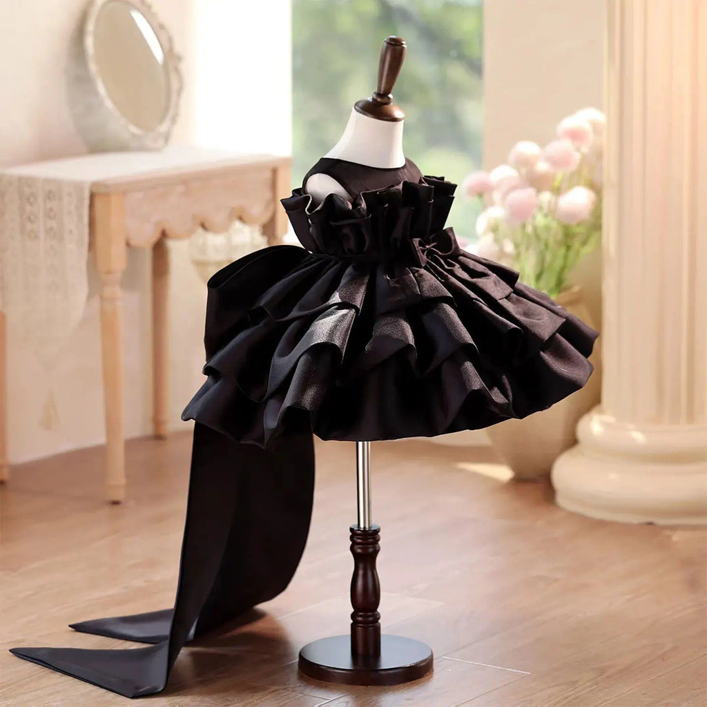 Black satin party dress for girls showing the standing ruffle collar and sheer yoke, angled front view.
