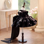 Black satin party dress for girls showing the standing ruffle collar and sheer yoke, angled front view.
