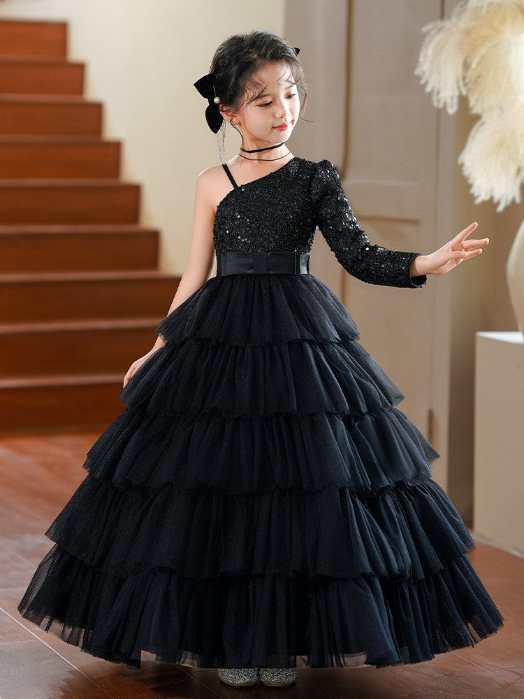 Girl in the black one shoulder sequin gown reaching out, full length view, for a recital.