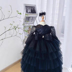Black sequin girls formal dress with sheer long sleeves and a tiered tulle ball skirt, front view, for a pageant.