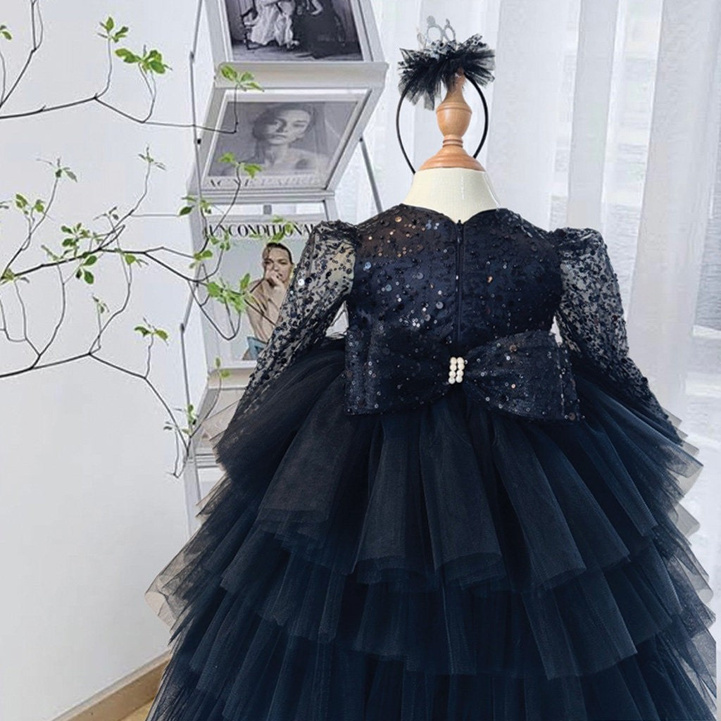 Black dress for girls showing the sequin bodice, bow waist and layered tulle tiers, angled view.