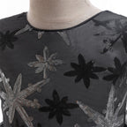 Close-up of the black mesh bodice with silver and black sequin star-flower embroidery and round neckline.