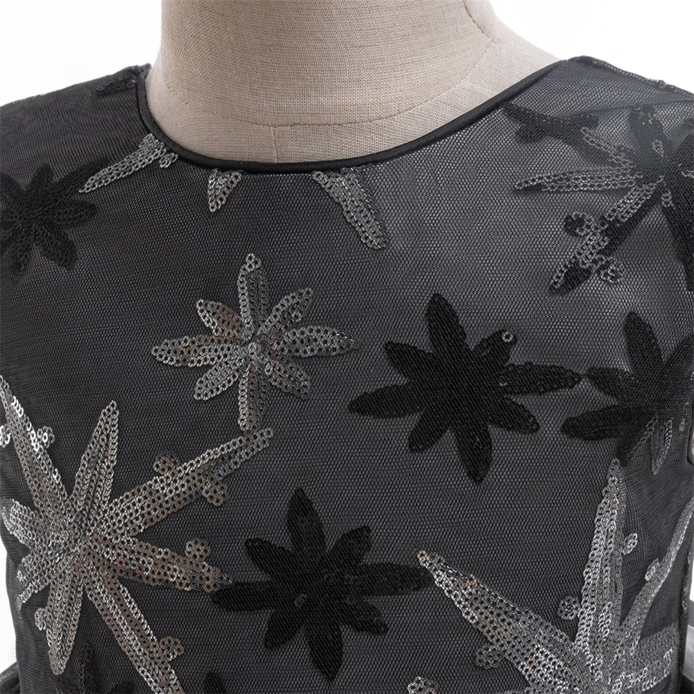 Close-up of the black mesh bodice with silver and black sequin star-flower embroidery and round neckline.
