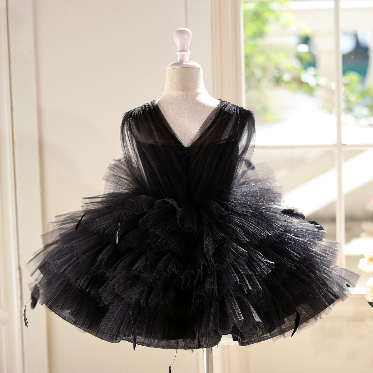Black tulle princess dress for girls showing the V-back with a concealed zipper, back view, styled for a photoshoot.