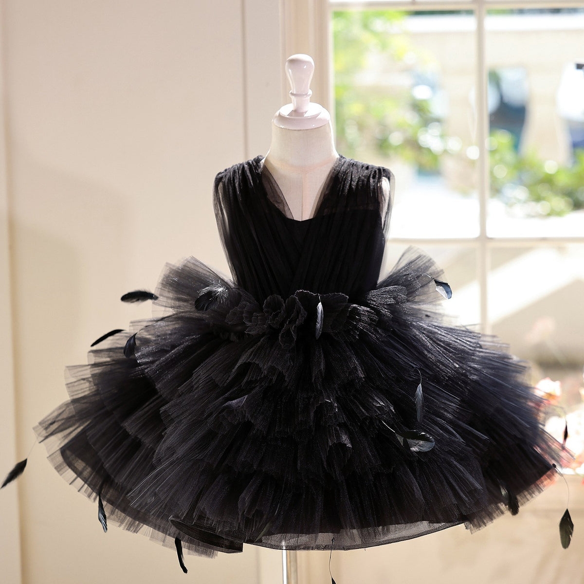 Black tulle girls party dress with feather accents and a tiered ruffled skirt, front view, for recitals and birthdays.