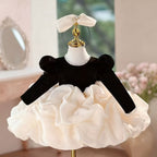 Long sleeve version of the black velvet girls party dress with its ivory organza bubble skirt, front view.