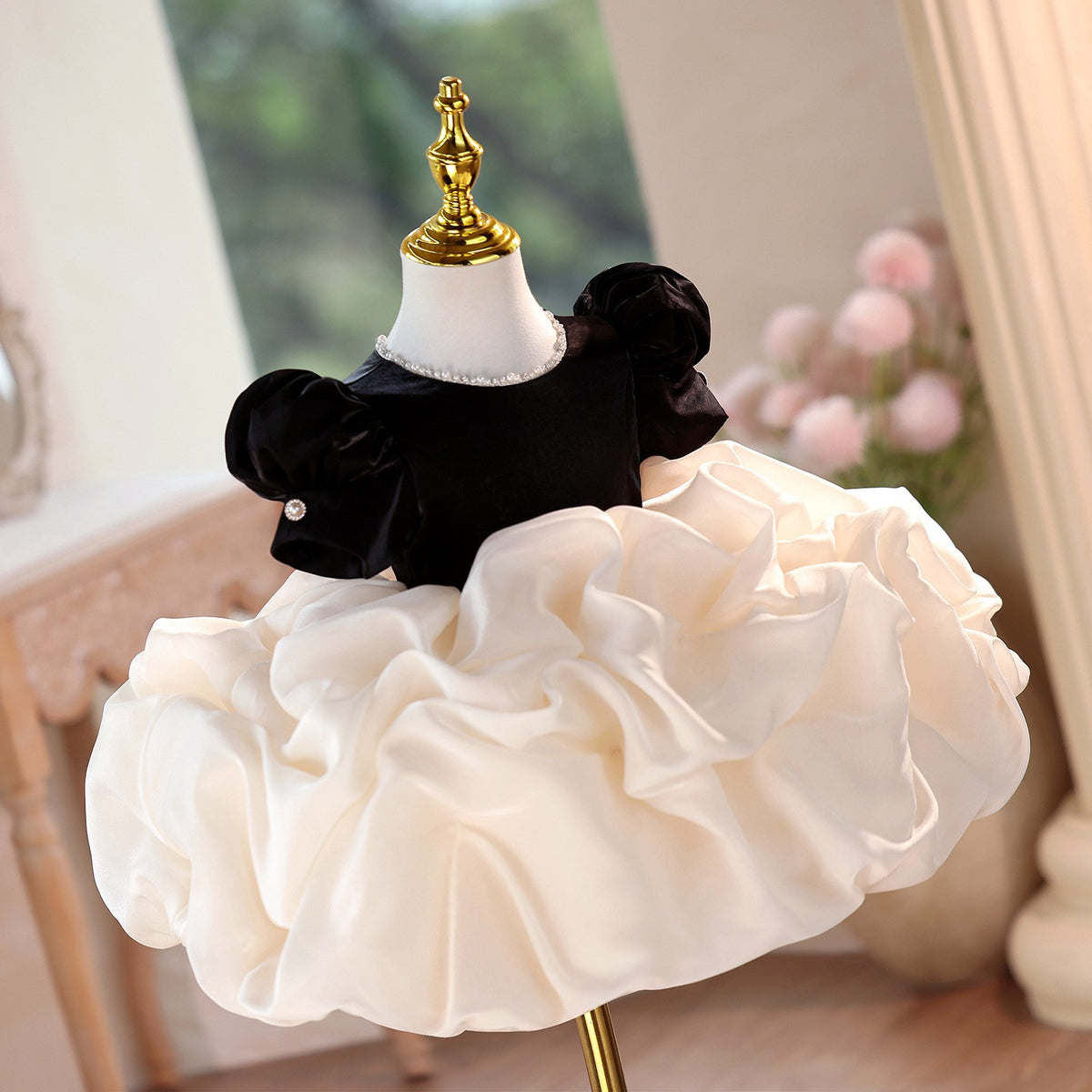 Pearl-trimmed neckline and velvet puff sleeves on the black and ivory girls formal dress, angled view.