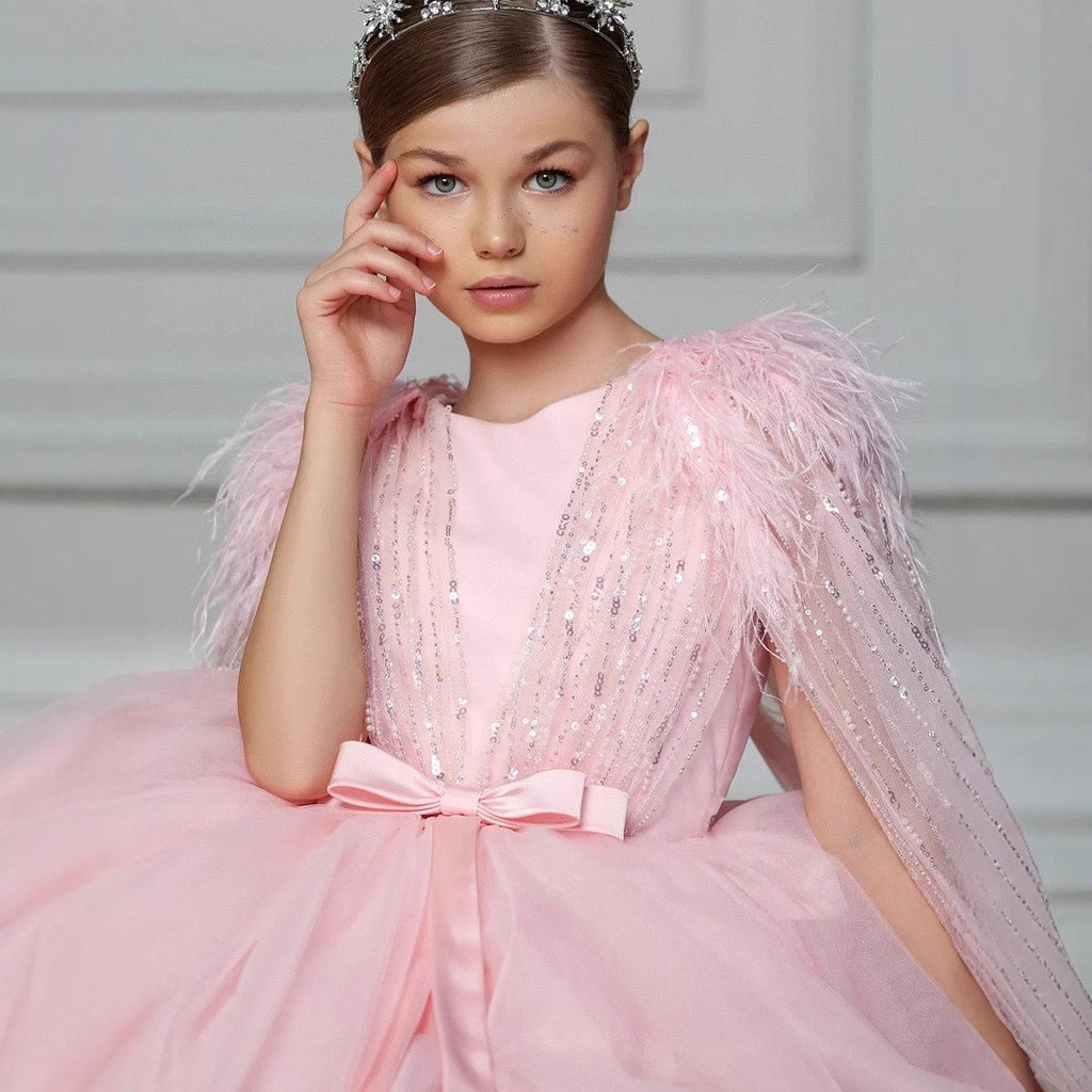 Pink tulle princess dress for girls with a sequin feather cape and satin bow sash, front view, for weddings and birthday parties.