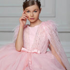 Pink tulle princess dress for girls with a sequin feather cape and satin bow sash, front view, for weddings and birthday parties.