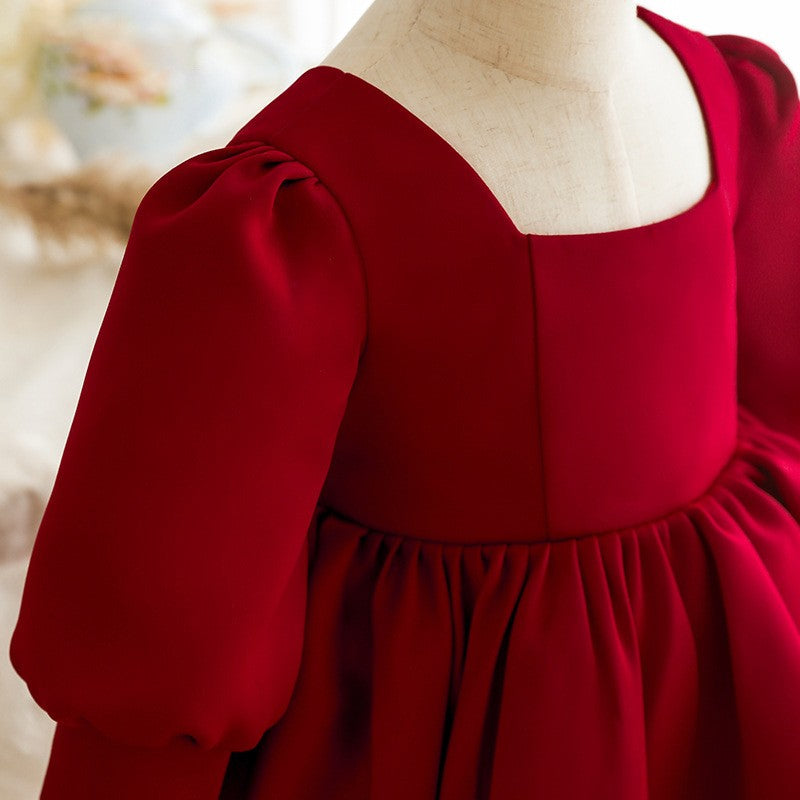 Close-up of the square neckline and gathered puff sleeve on the burgundy satin girls party dress.