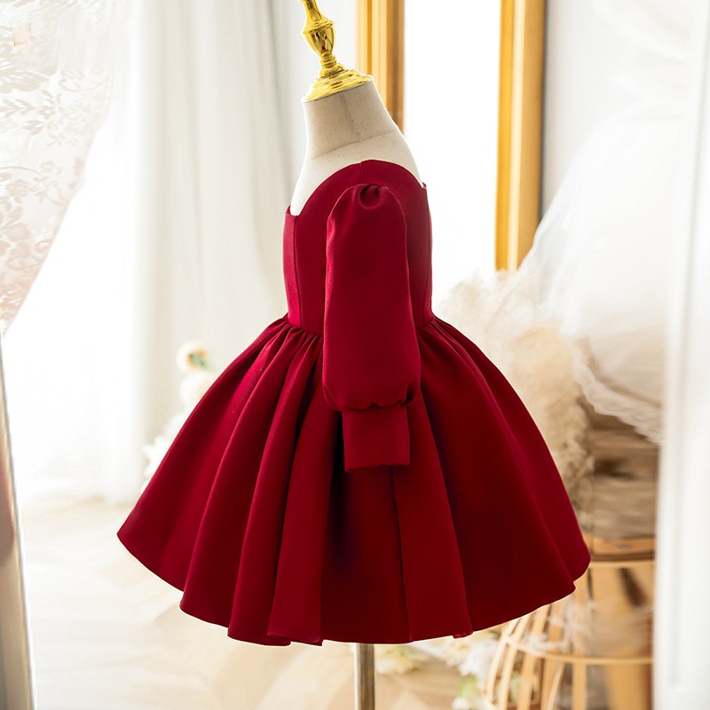 Burgundy satin girls party dress with a gathered full skirt and puff sleeve, side view, one of our girls formal dresses.