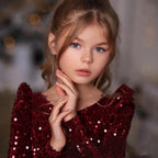 Close-up of the burgundy sequin fabric and the wide boat neckline on this girls holiday dress.