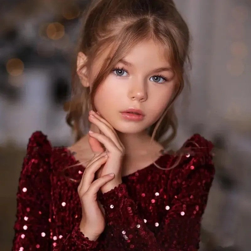 Close-up of the burgundy sequin fabric and the wide boat neckline on this girls holiday dress.