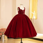 Burgundy velvet princess dress for girls with beaded shoulder straps, angled side view, for Christmas parties.