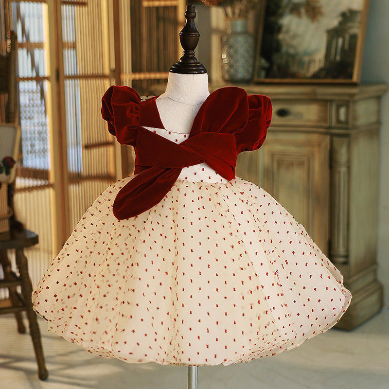 Burgundy and champagne velvet girls dress with crossed velvet bodice, puff sleeves and dotted tulle skirt, designed for holiday parties.