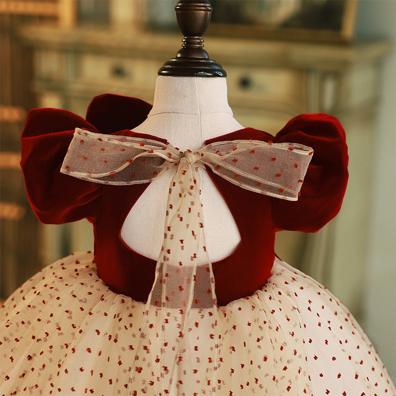 Burgundy velvet girls dress with puff sleeves and sheer dotted bow at the open back, designed for holiday events.