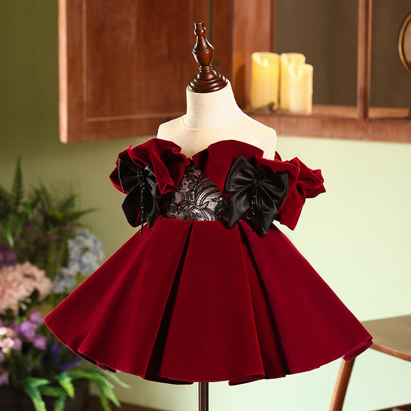 Close-up of the black floral lace bodice and the two black satin bows with beaded tassels on the burgundy velvet girls party dress.