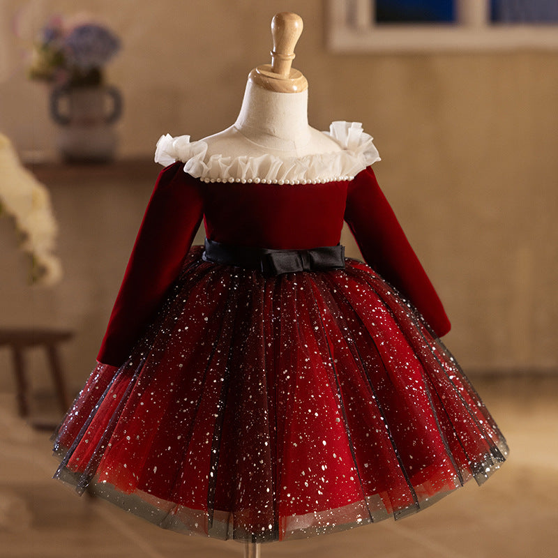 Burgundy velvet girls holiday dress with long sleeves, pearl trim and a black satin bow at the waist, designed for Christmas photos.