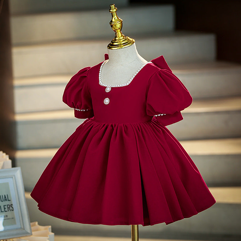 Burgundy velvet girls dress with a pearl-trimmed square neckline, puff sleeves and pearl buttons, designed for Christmas and holiday parties.