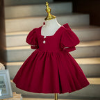 Burgundy velvet girls dress with a pearl-trimmed square neckline, puff sleeves and pearl buttons, designed for Christmas and holiday parties.