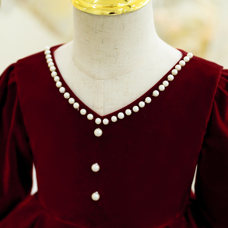 Burgundy velvet girls dress with a pearl-edged V-neck and pearl buttons down the bodice, designed for Christmas, weddings and photos.