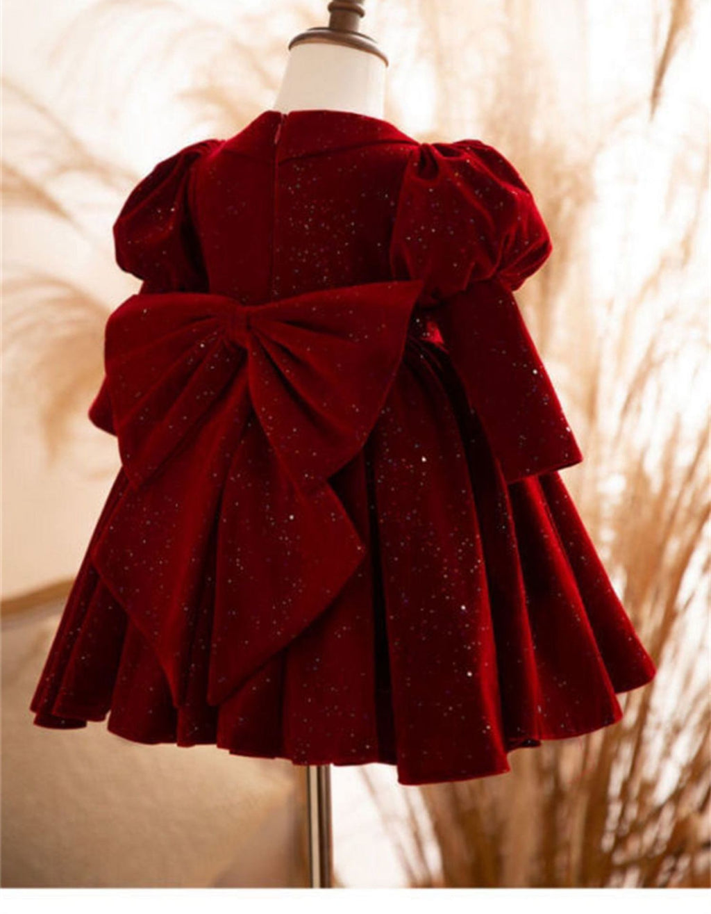 Back view of the burgundy velvet girls party dress showing the wide velvet bow tied over the full skirt.