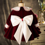 Back view of the burgundy velvet girls party dress showing the large ivory satin bow.