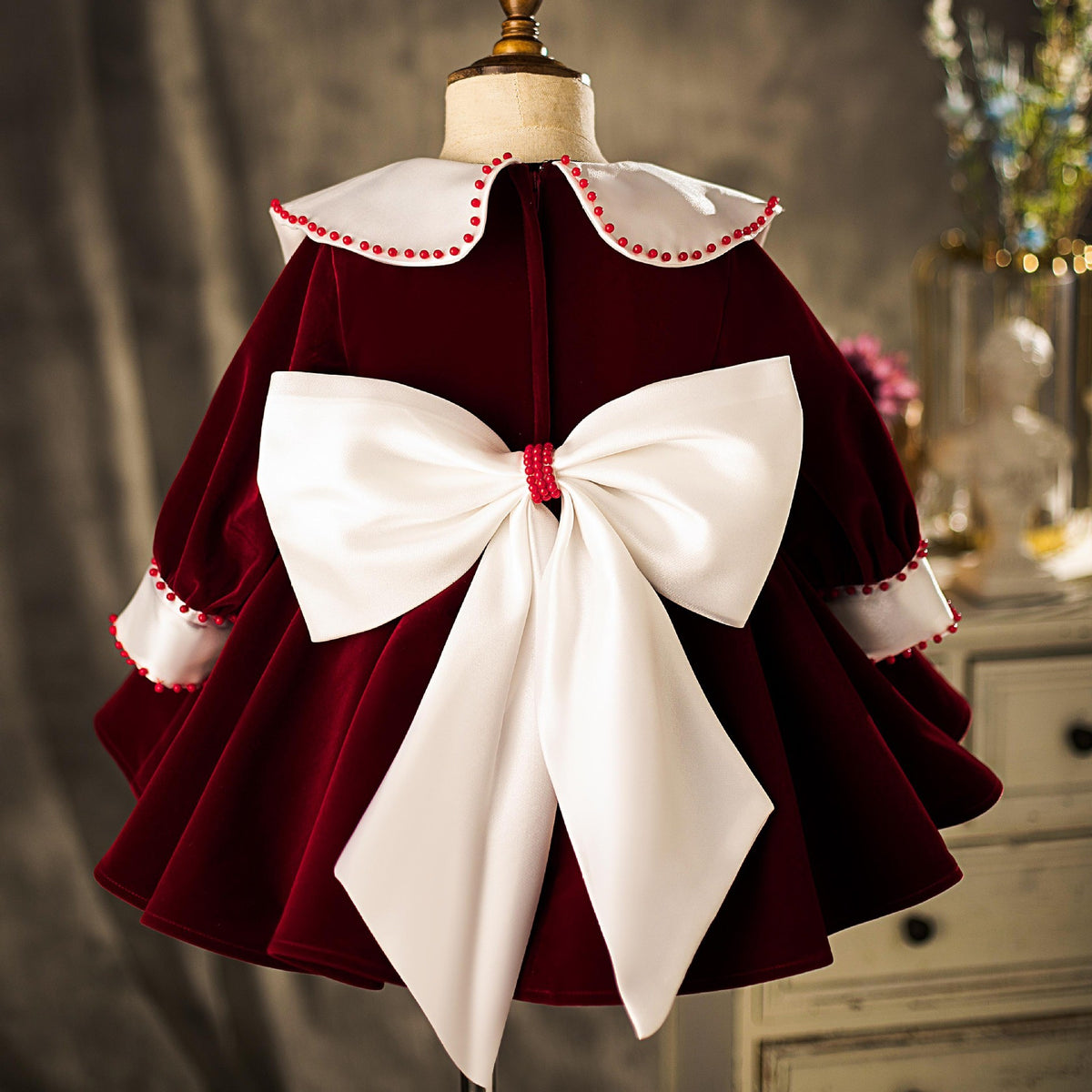 Back view of the burgundy velvet girls party dress showing the large ivory satin bow.