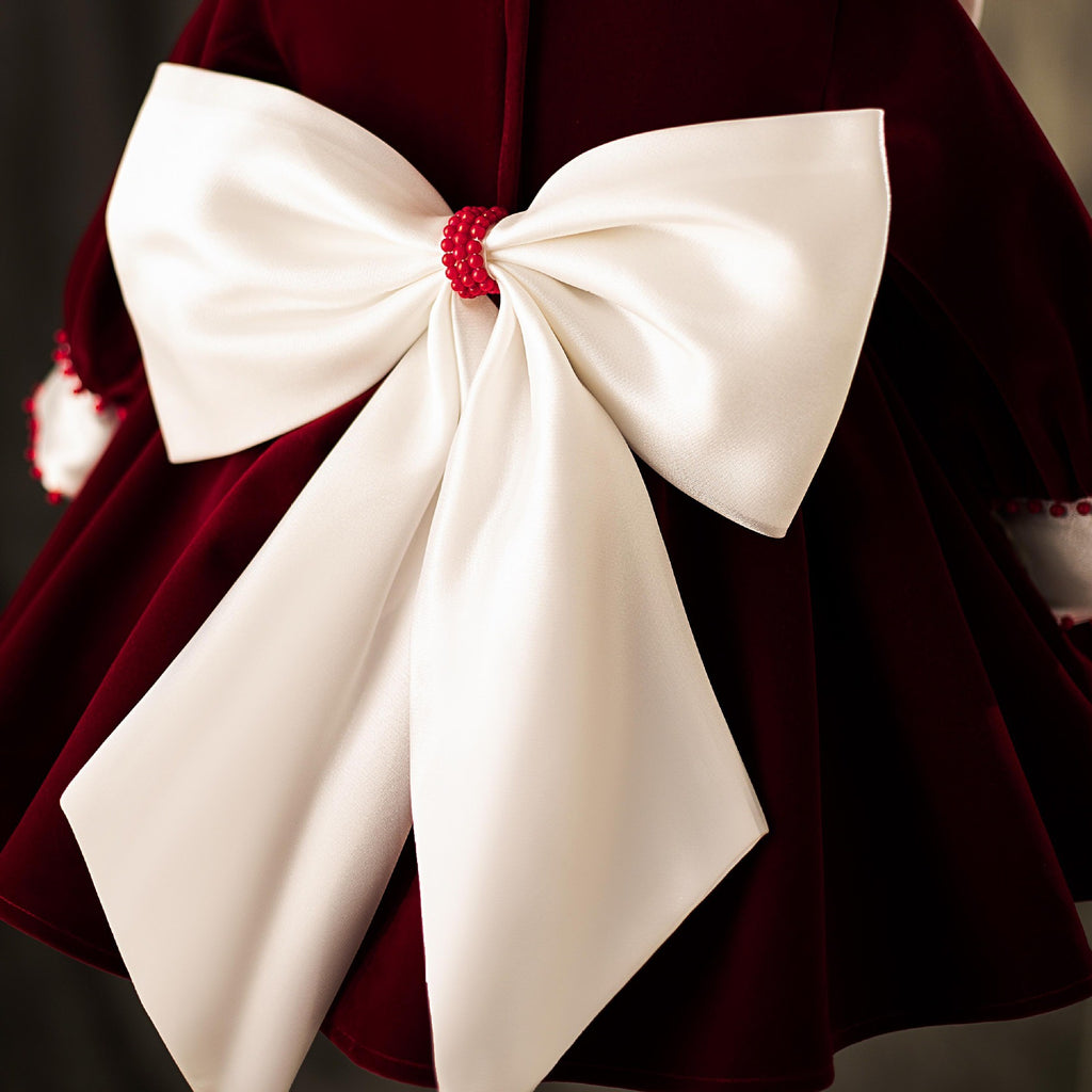 Close-up of the ivory satin bow with its beaded centre on the back of the velvet dress.