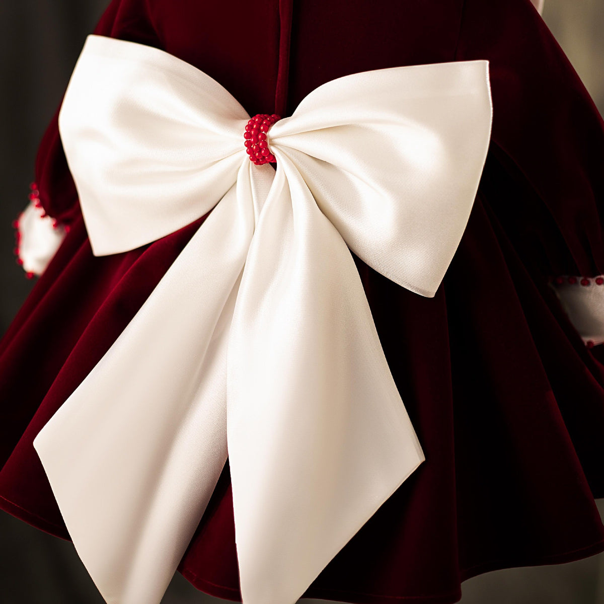 Close-up of the ivory satin bow with its beaded centre on the back of the velvet dress.
