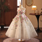Champagne tulle girls gown with pink and blue 3D flowers cascading from the bodice, designed for weddings and birthdays.
