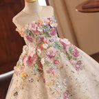 Champagne tulle girls gown with close-up 3D fabric flowers, embroidery and sequins, designed for flower girls and photoshoots.