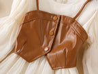 Front of the brown faux leather bustier vest with button front over the cream chiffon girls dress, designed for birthday parties.