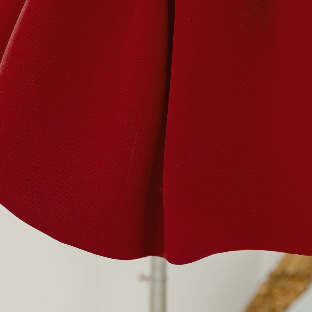 Close-up of the soft deep red fabric of the girls dress skirt.
