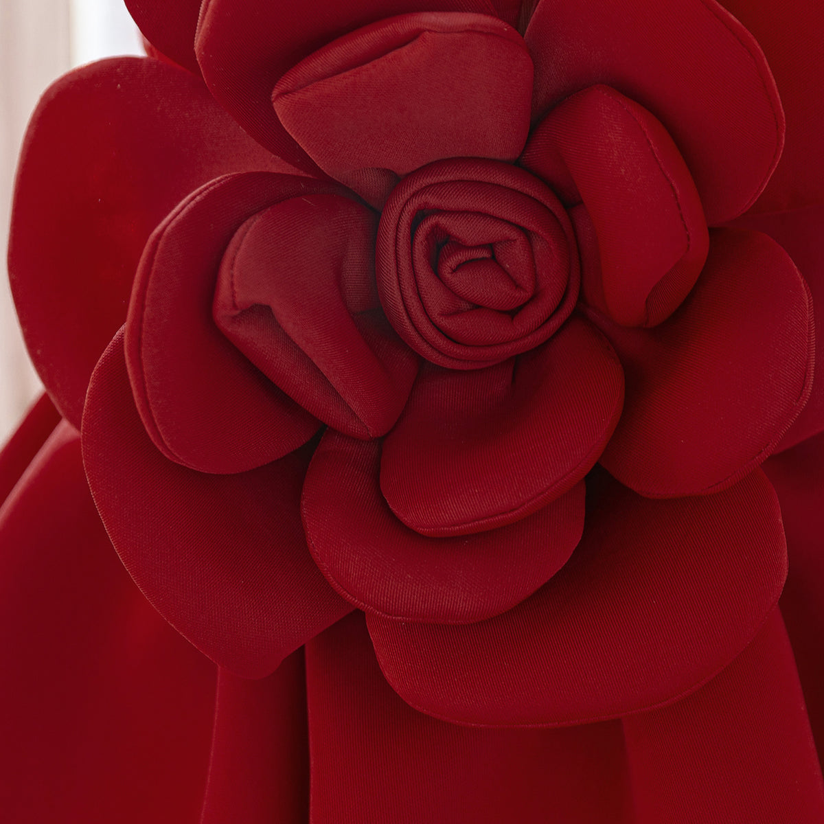Detail of the layered petals on the rose appliqué of the deep red girls dress.