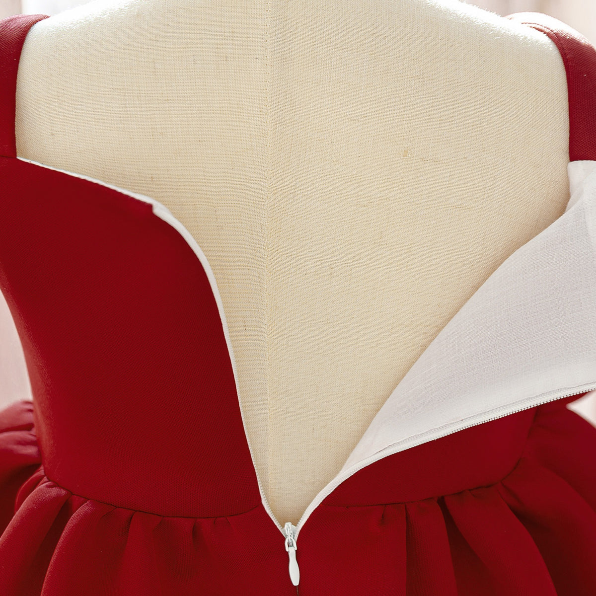 Close-up of the back zipper and white lining of the deep red girls dress.