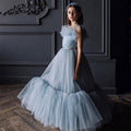 Dusty blue tulle flower girl dress with a ruffled neckline and beaded belt, front view, for a wedding.