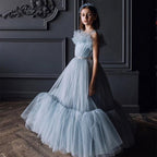 Dusty blue tulle flower girl dress with a ruffled neckline and beaded belt, front view, for a wedding.