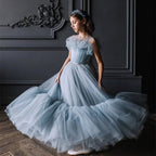 Dusty blue tiered tulle gown with the skirt in motion, side view, for a ceremony.