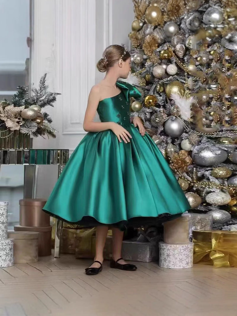 Emerald green satin girls dress with oversized shoulder bow and tulle underlayer, designed for pageants and recitals.
