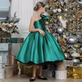 Emerald green satin girls dress with one-shoulder bow and beaded flowers, designed for Christmas parties.