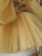 Golden yellow tulle girls dress with rosette and bead embroidery on a pleated bodice, designed for birthdays and photoshoots.